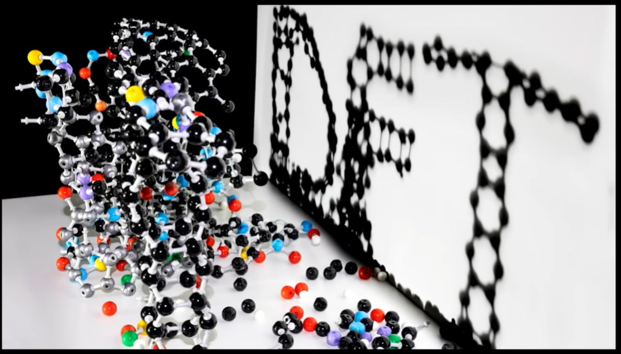 Complex molecular model casting a shadow that spells "DFT" — DFT is the theoretical projection behind molecular structure | Source: Benjamin Li